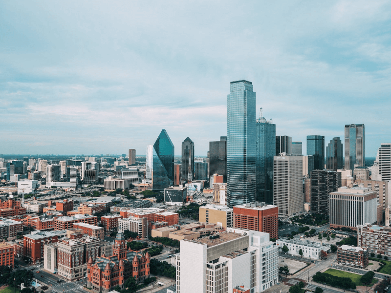 Towers and brick-colored mid-rise buildings make up the skyline in Dallas on an overcast day