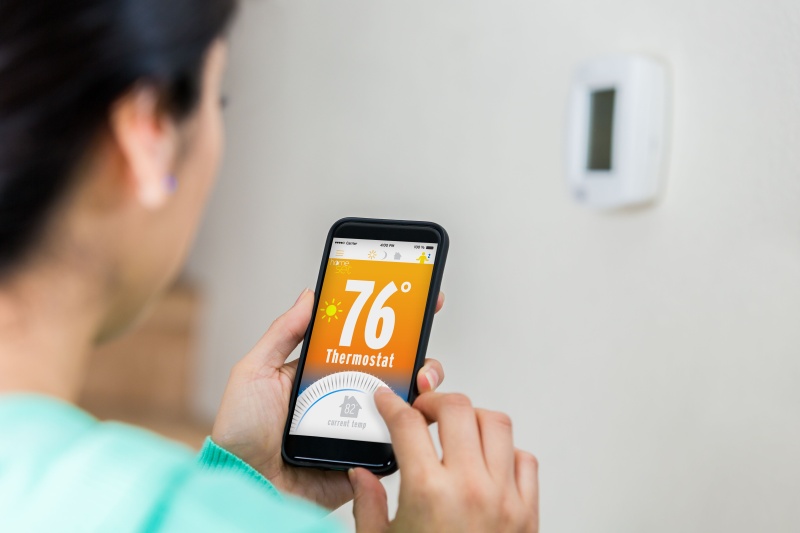 Woman uses smart phone to control thermostat